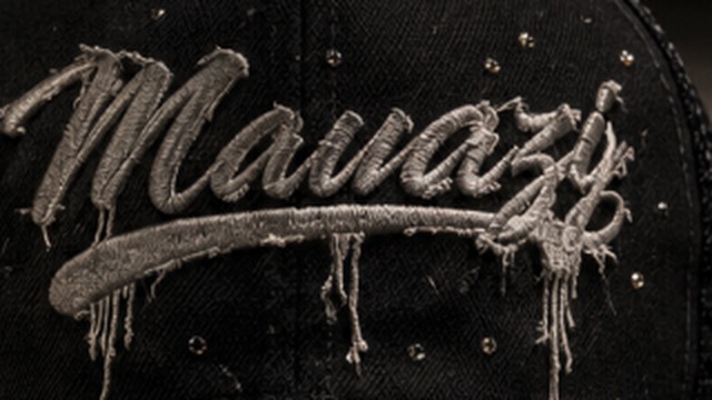 Close-up of the Mavazi script embroidery in metallic thread on black distressed fabric